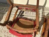 a wooden rocking chair with a red seat next to a wooden rocking chair