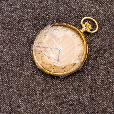une montre de poche en or posée sur un tissu marron