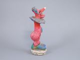 sculpture of a pink and blue bird on a rock on a gray background