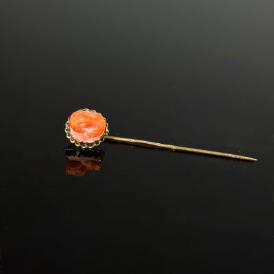 a gold and coral colored broochle broochle on a black surface