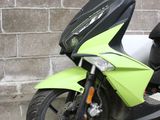a green scooter parked in front of a brick building