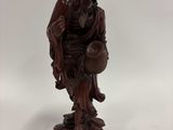 une vieille statue en bois représentant un homme assis sur un rocher