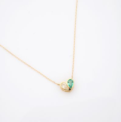 un collier en or avec un pendentif en forme de cœur vert sur fond blanc