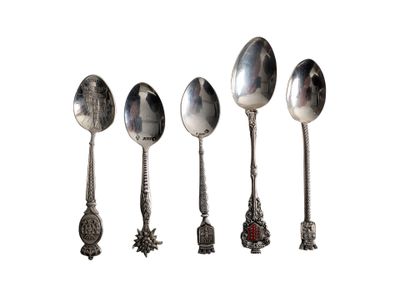 four silver spoons are lined up in a row on a white surface