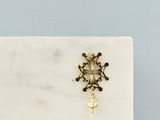 La boucle d'oreille en forme de flocon de neige doré repose sur une plaque de marbre blanc