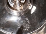 a silver plate with a bird on it on a black table