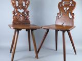 deux chaises en bois aux dossiers sculptés sont disposées côte à côte sur un fond gris