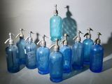 Plusieurs bouteilles en verre bleu équipées de distributeurs de savon sont alignées sur une table