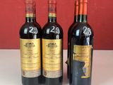 trois bouteilles de vin sont posées sur un comptoir devant un mur rouge