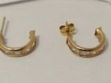 une paire de boucles d'oreilles plaquées or et un nœud papillon posés sur une table blanche