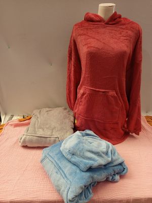 un lit recouvert d'une couverture rose et d'un sweat à capuche rouge posé dessus