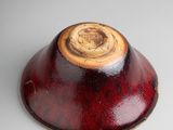 a red bowl with a wooden lid on a white surface