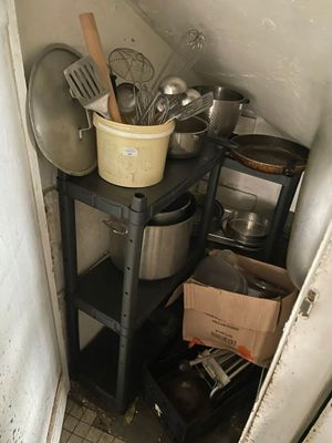 Des casseroles et des poêles sont empilées sur une étagère dans un coin de la cuisine.