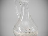 a clear glass vase with a curved handle on a table