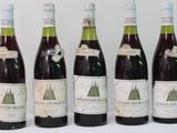 six bottles of wine are lined up in a row on a white surface