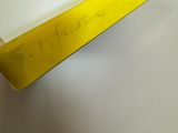 someone is holding a yellow ruler with a black handle on a white surface