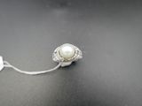 un gros plan d'une bague ornée d'une perle sur un fond noir