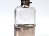 a small glass bottle with a silver lid on a white surface
