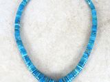a close up of a necklace with blue beads on a white surface