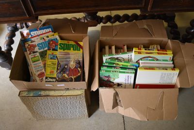 two boxes of books sitting on the floor next to a table