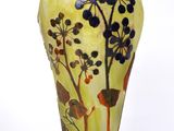 a yellow vase with blue flowers and leaves on it