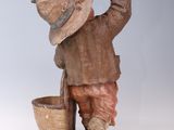a wooden statue of a boy with a bucket and a bird