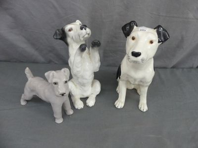 trois figurines de chiens assis sur une surface grise