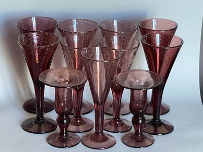six verres à vin posés sur une table, à côté d'un vase