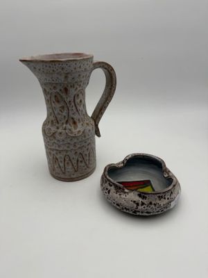 a small pitcher and a small bowl sitting next to each other