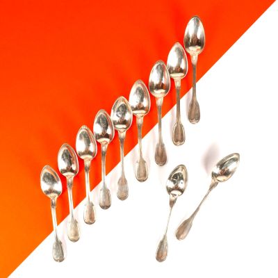 Plusieurs cuillères et cuillères-cuillères sont alignées sur un plan de travail orange et blanc