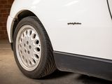 a white car parked in a garage with a brick wall behind it
