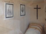 reflection of a bedroom with a bed and a cross on the wall