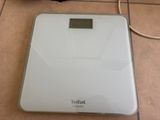 a bathroom scale that is on the floor next to a bag