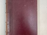 an old red book sitting on top of a white table
