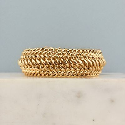 un gros plan d'un bracelet en or posé sur une surface en marbre