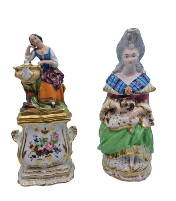 two figurines of women sitting on top of each other
