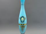 une image représentant un vase bleu orné d'une bordure dorée, posé sur un socle blanc