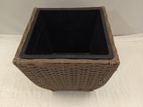 a wicker basket with a black lid on a white surface