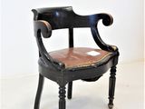 une chaise noire avec une assise en cuir marron posée sur un sol blanc