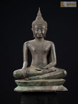 une statue en bronze représentant un Bouddha assis sur un rocher