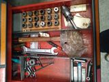une boîte à outils rouge contenant des outils, avec une personne debout à côté