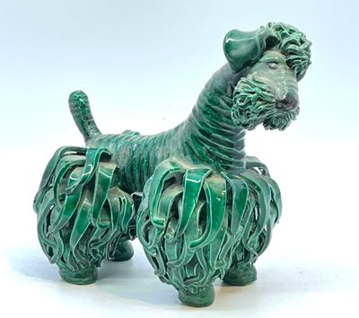 une petite statue de chien verte posée sur une surface blanche