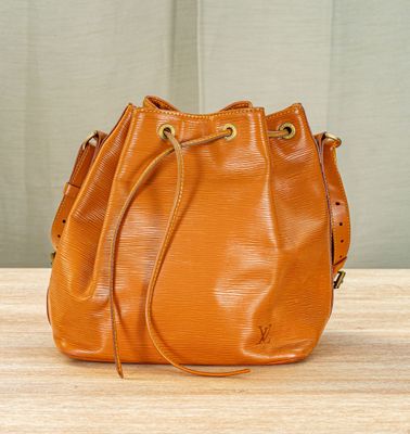 an orange bucket bag sitting on top of a wooden table