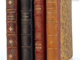 several old books are stacked on top of each other on a white surface