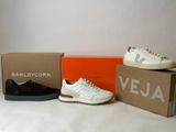 three pairs of white and black sneakers sitting on top of a box
