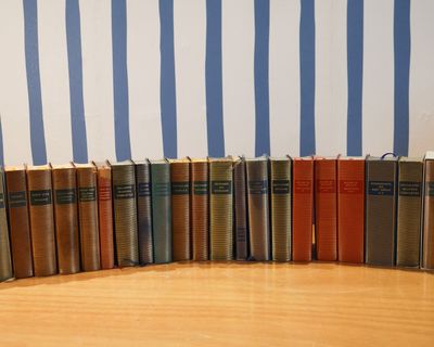 des livres alignés sur une table en bois devant un mur rayé