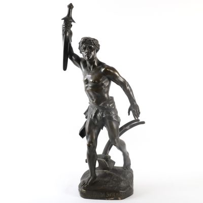 an antique bronze statue of a man holding a sword on a white background