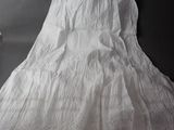a white dress hanging on the wall next to a vase of flowers