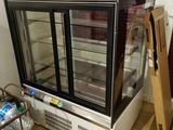 des bouteilles d'eau sont posées par terre à côté d'une vitrine réfrigérée