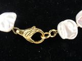 pearl necklace with gold clasp and clasp on black velvet background